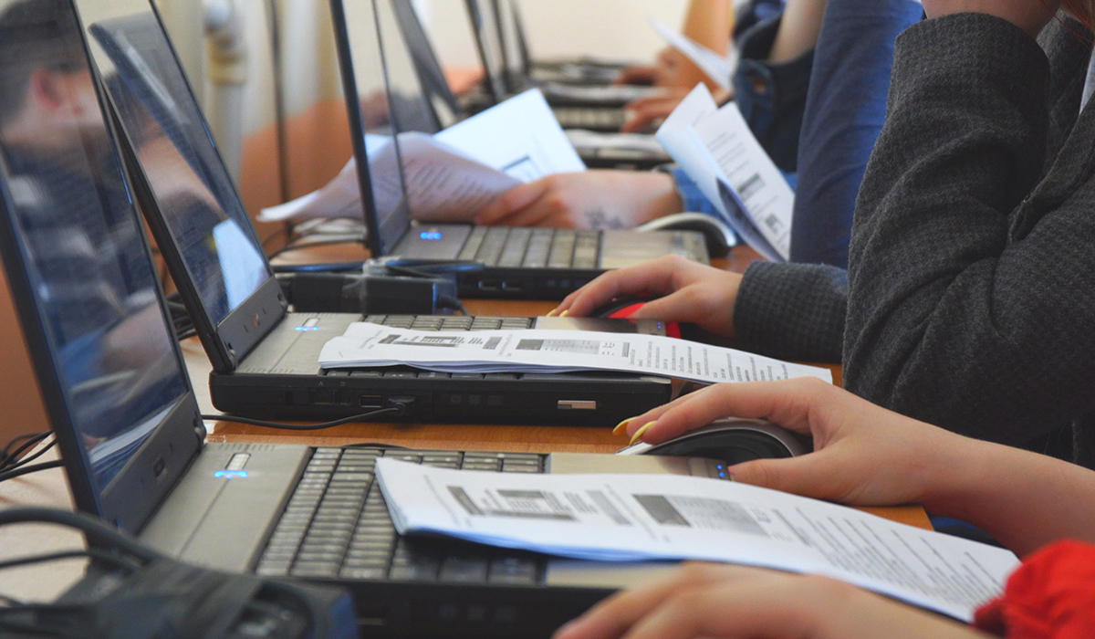 Students using their laptops and reading papers